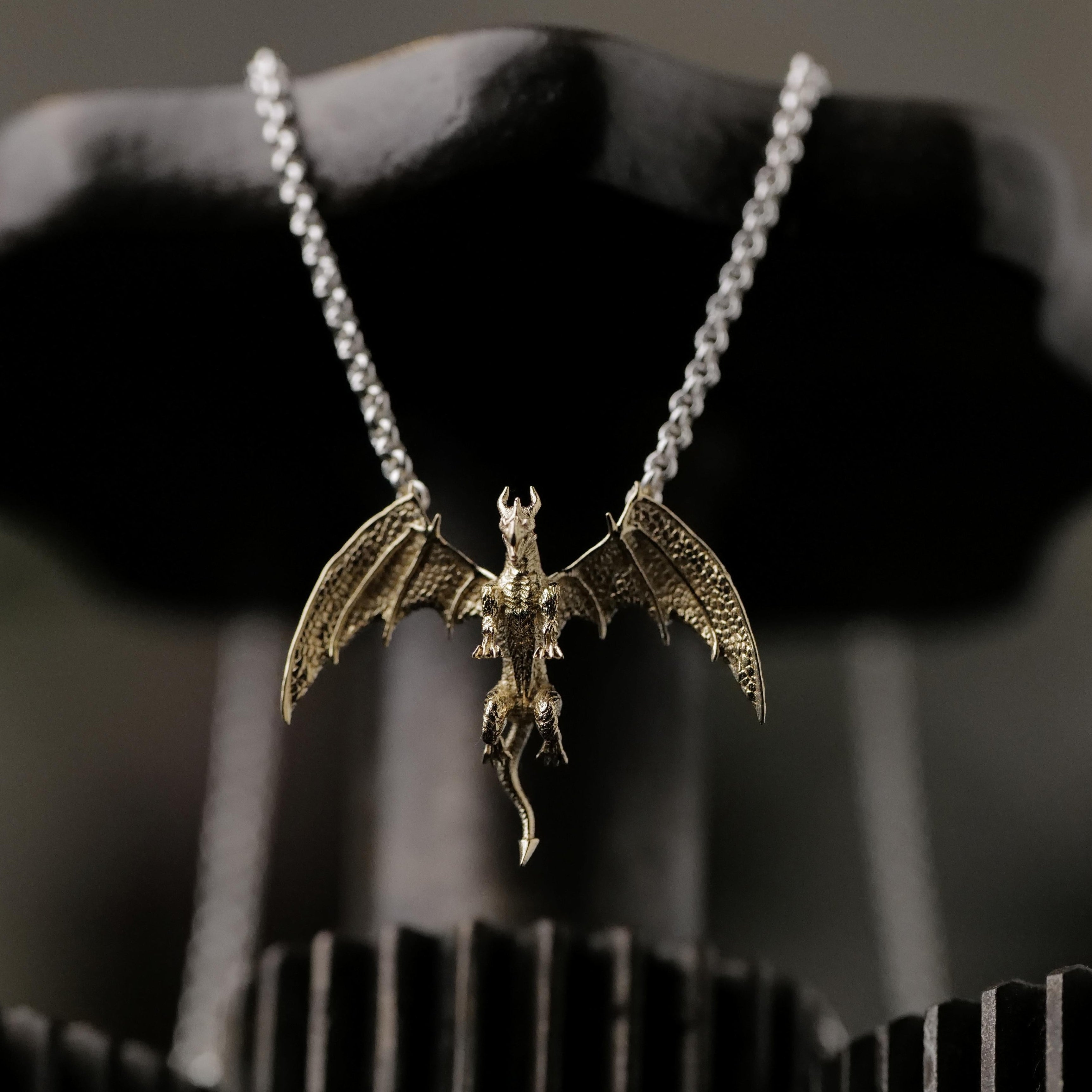 Fiat Lux’s Medieval Dragon Necklace (G) features a rune-etched 10K gold charm on a silver chain.