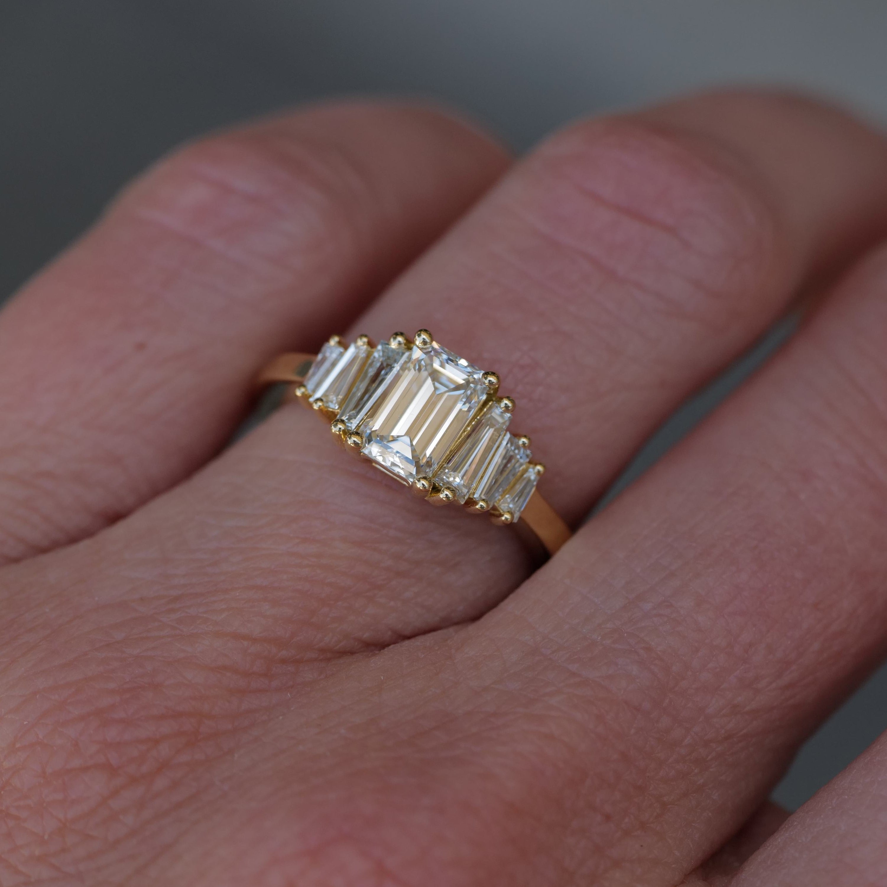 A Fiat Lux Classic Calypso ring with a 1.02ct emerald cut diamond is worn on a persons finger.