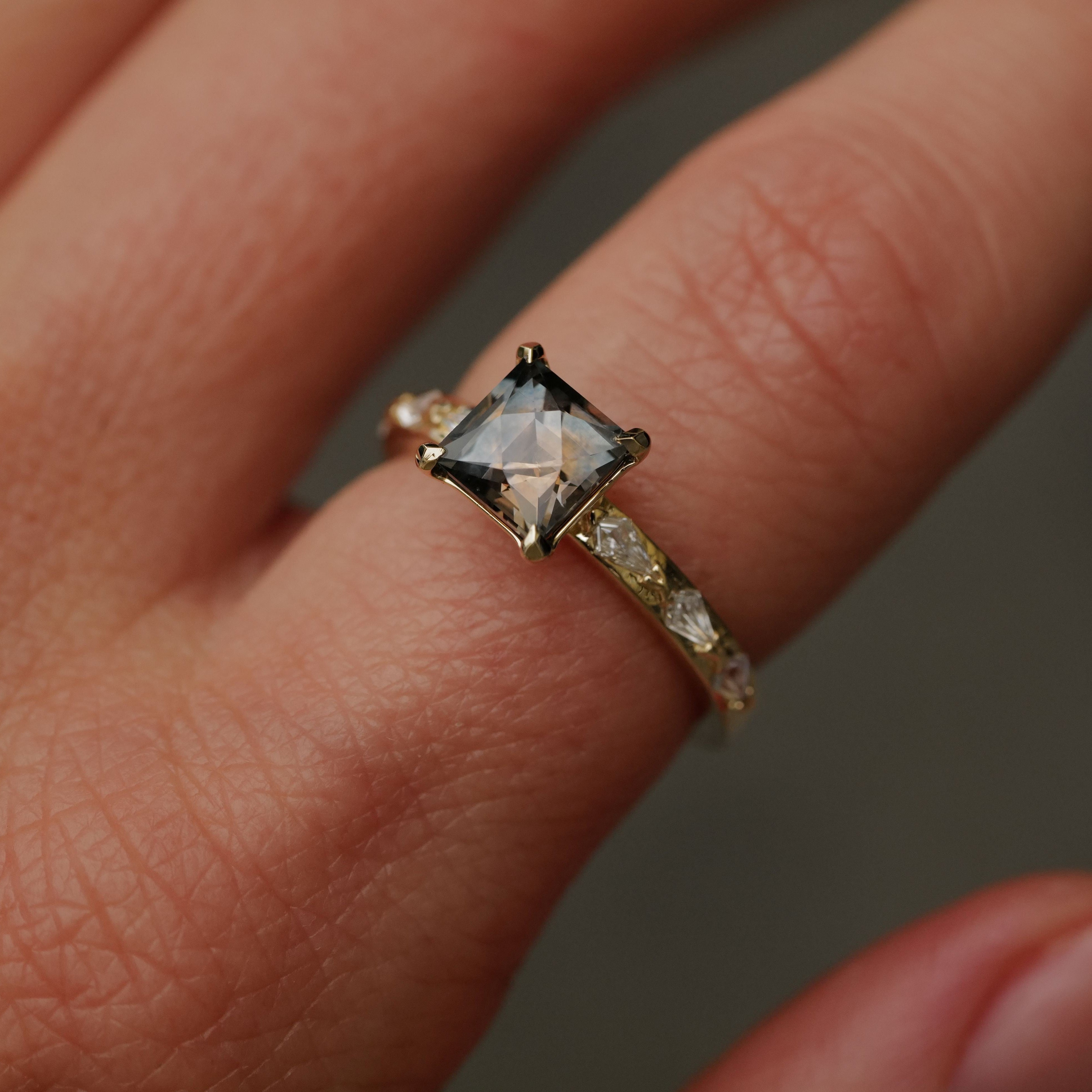 A hand wears the Fiat Lux Classic Theia Ring with a 1.70ct plum sapphire and diamond accents on the gold band.