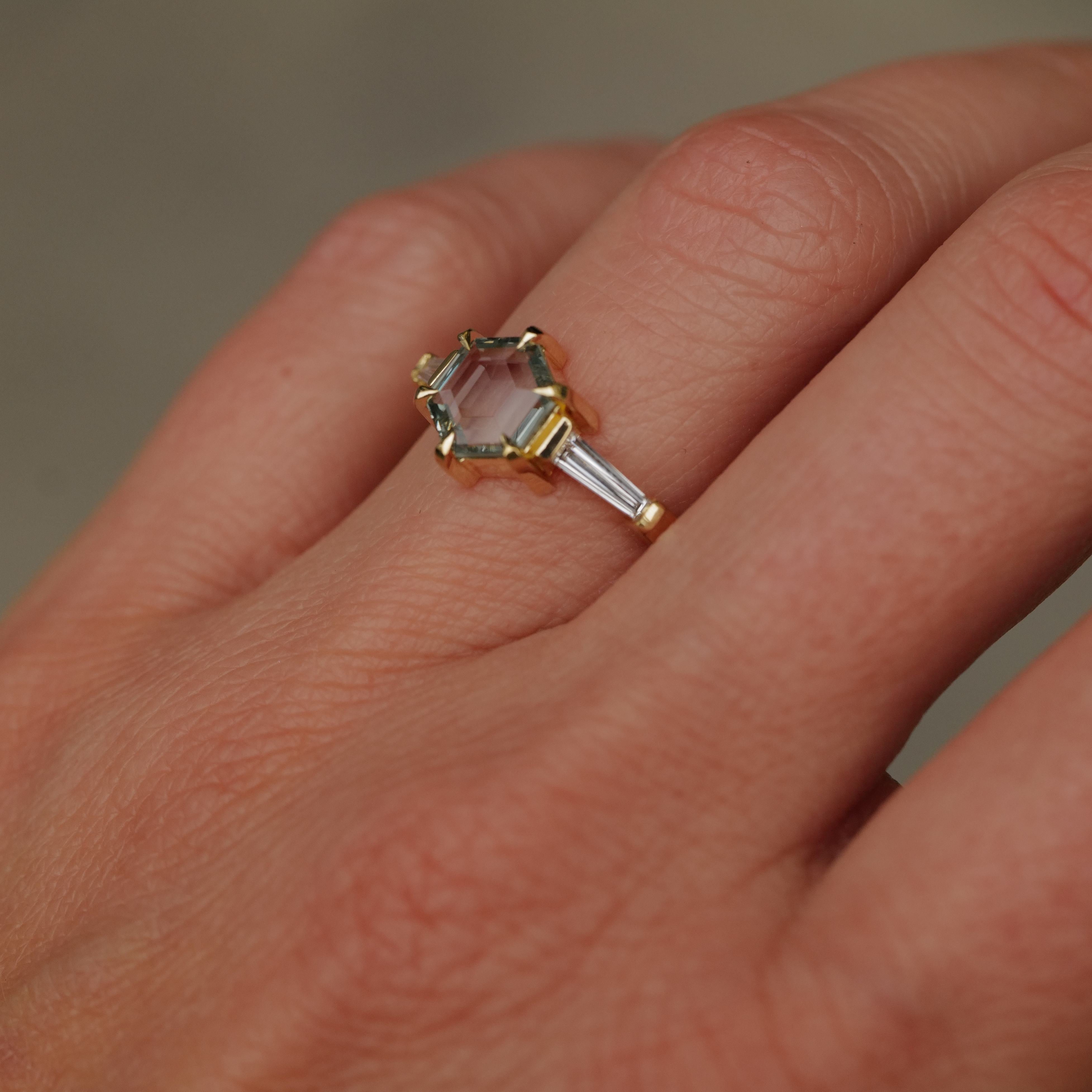 A hand wearing Fiat Luxs Grande Calliope ring with a seafoam green hexagon sapphire and baguette diamonds.