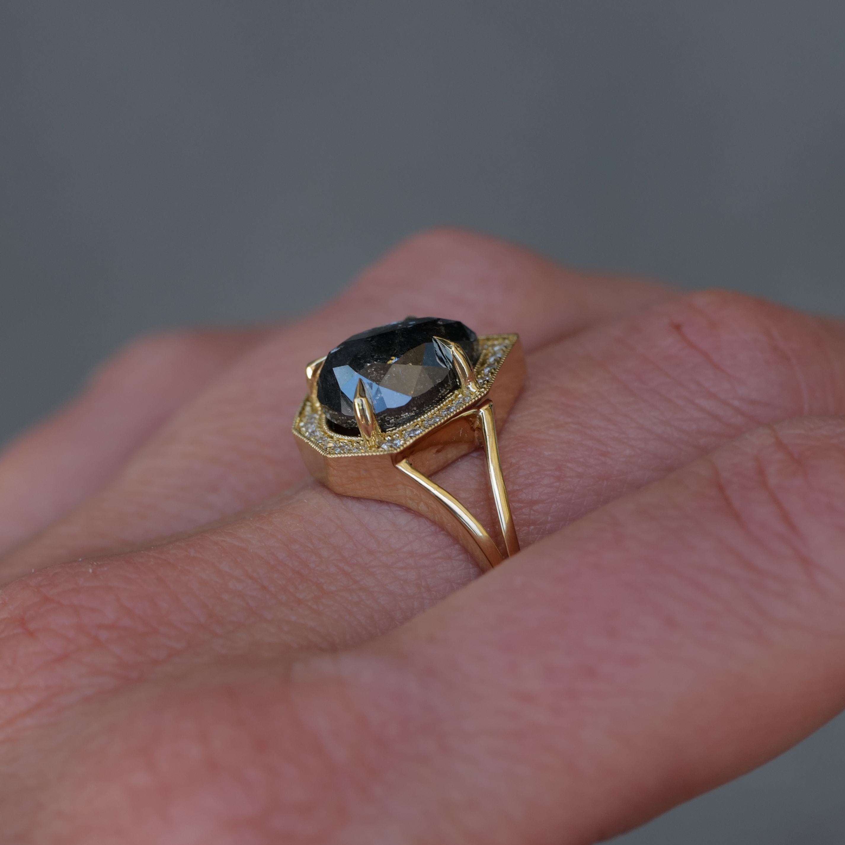 A hand wears Fiat Lux’s Grande Phoebe 18K gold ring with a 4.88ct salt & pepper diamond in a hexagonal setting.
