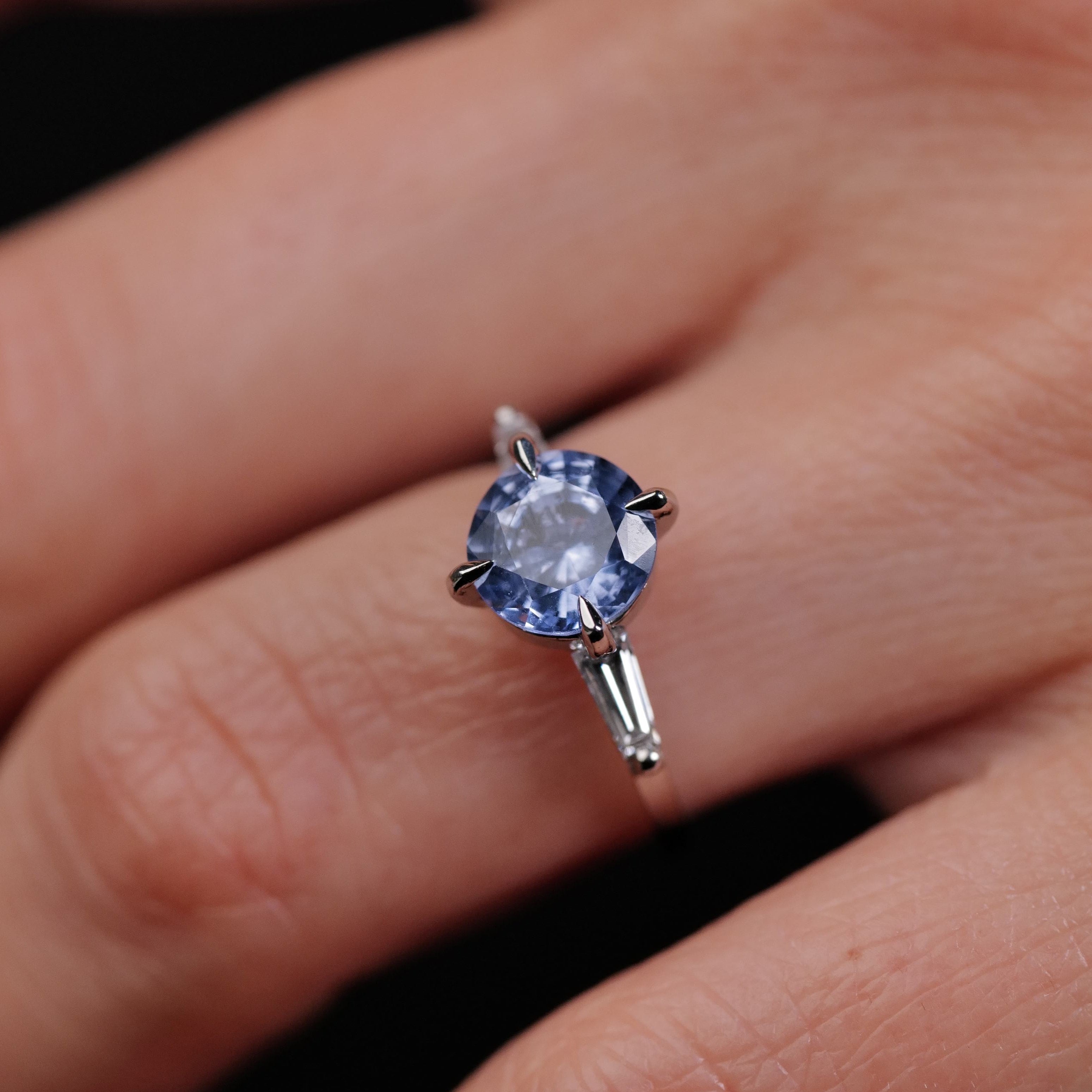 A hand wearing Fiat Luxs Grande Calliope ring with a 2.05ct periwinkle blue sapphire centerpiece.