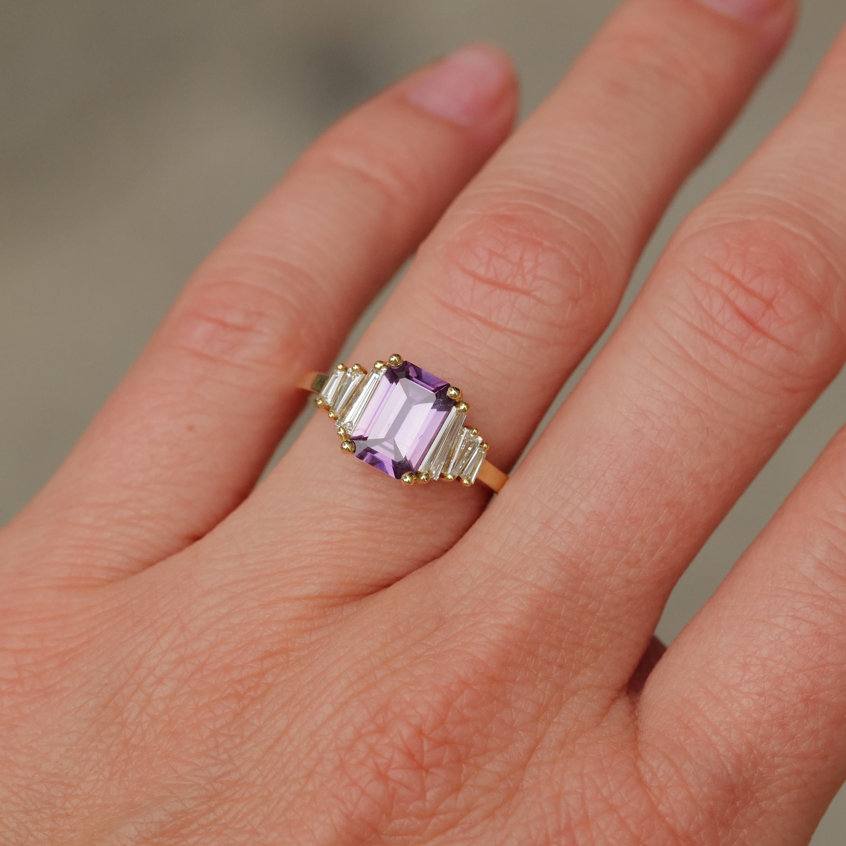 A hand wears Fiat Lux’s Grande Calypso ring: 18K gold, mulberry pink sapphire (1.94ct), and diamond baguettes.