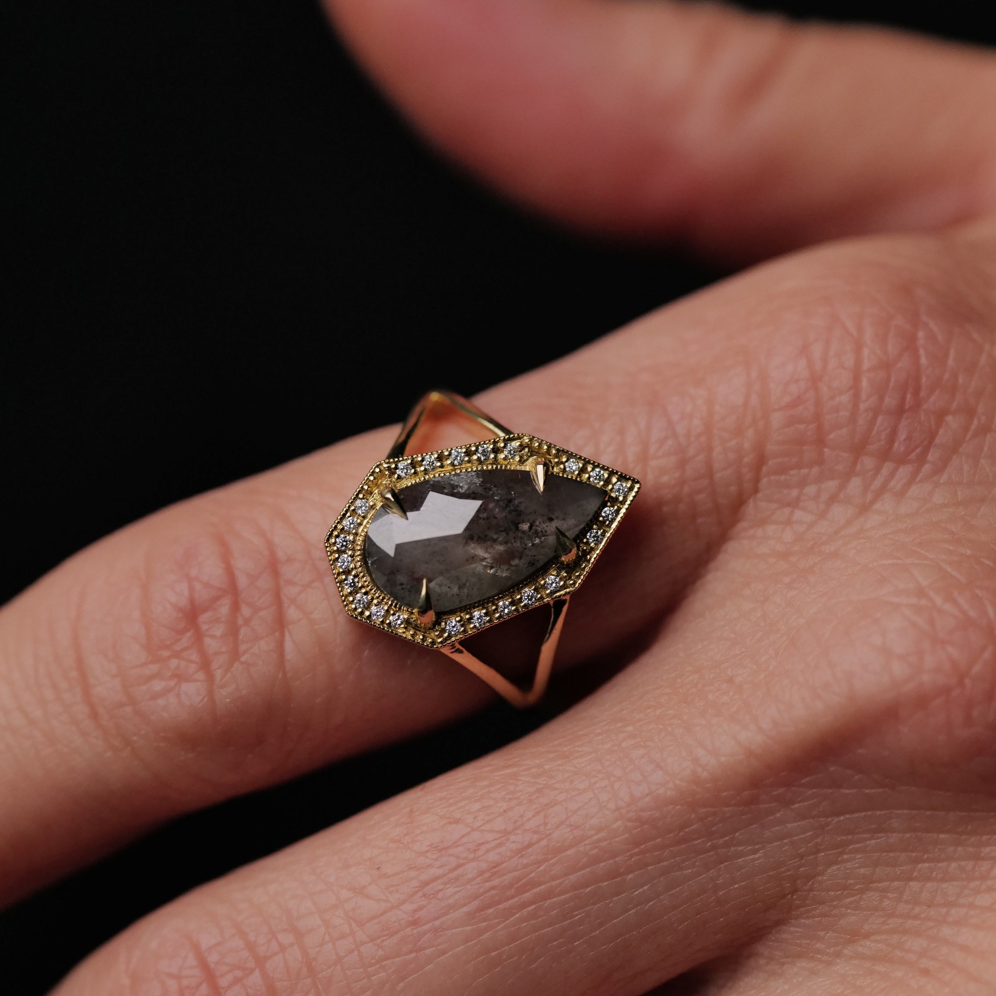 A hand wears Fiat Lux’s Grande Phoebe Ring with a 2.34ct soft grey salt & pepper diamond and sparkling stones.
