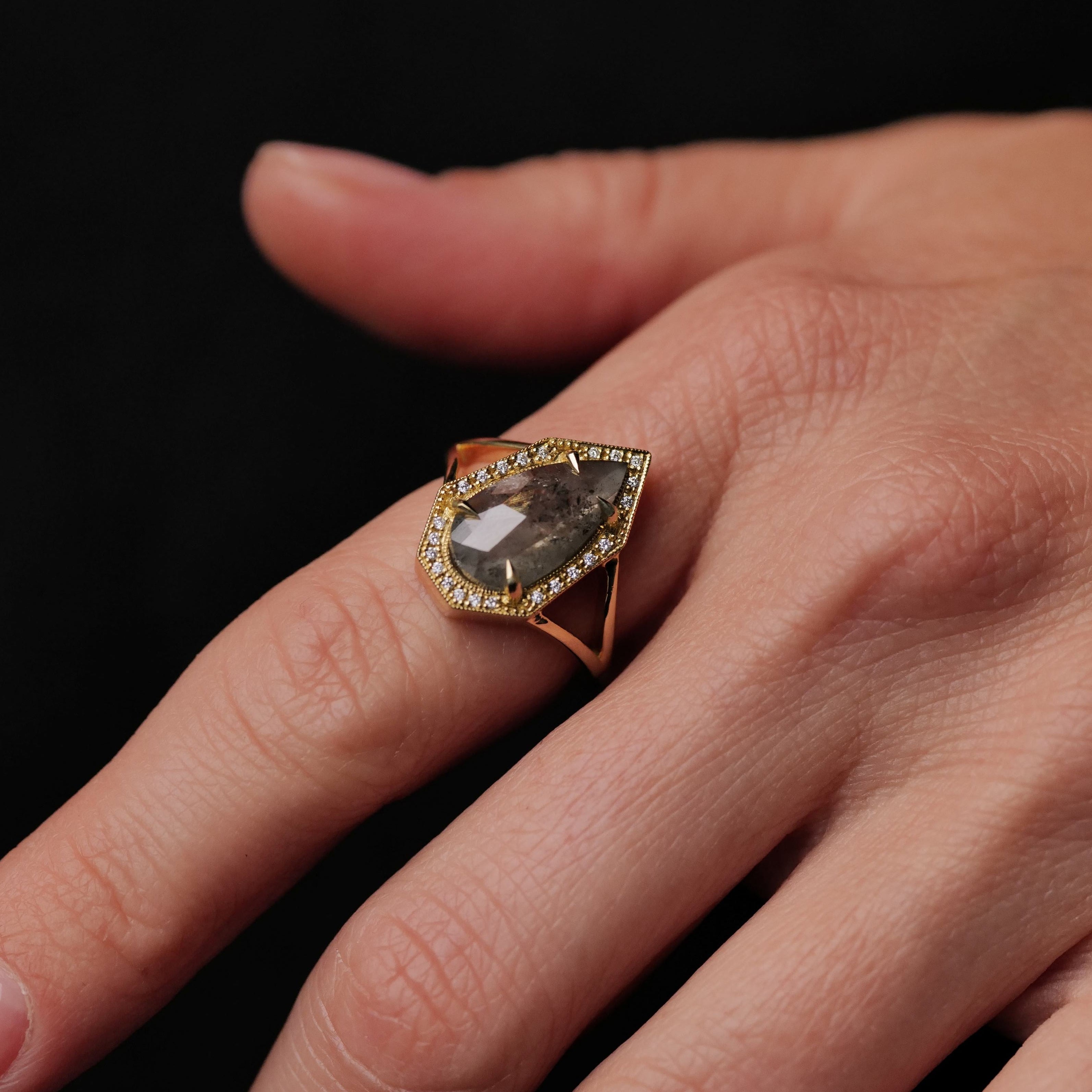 A hand wearing Fiat Luxs Grande Phoebe Ring with a 2.34ct soft grey salt & pepper diamond and small diamonds.