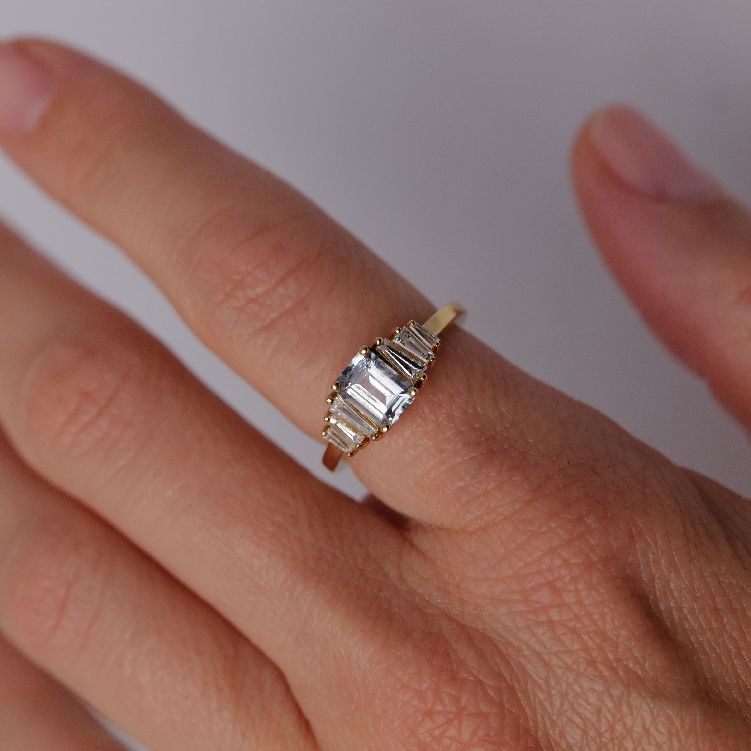 A Petite Calypso - Ice Blue Sapphire (1.16ct) ring by Fiat Lux is worn on a persons finger.