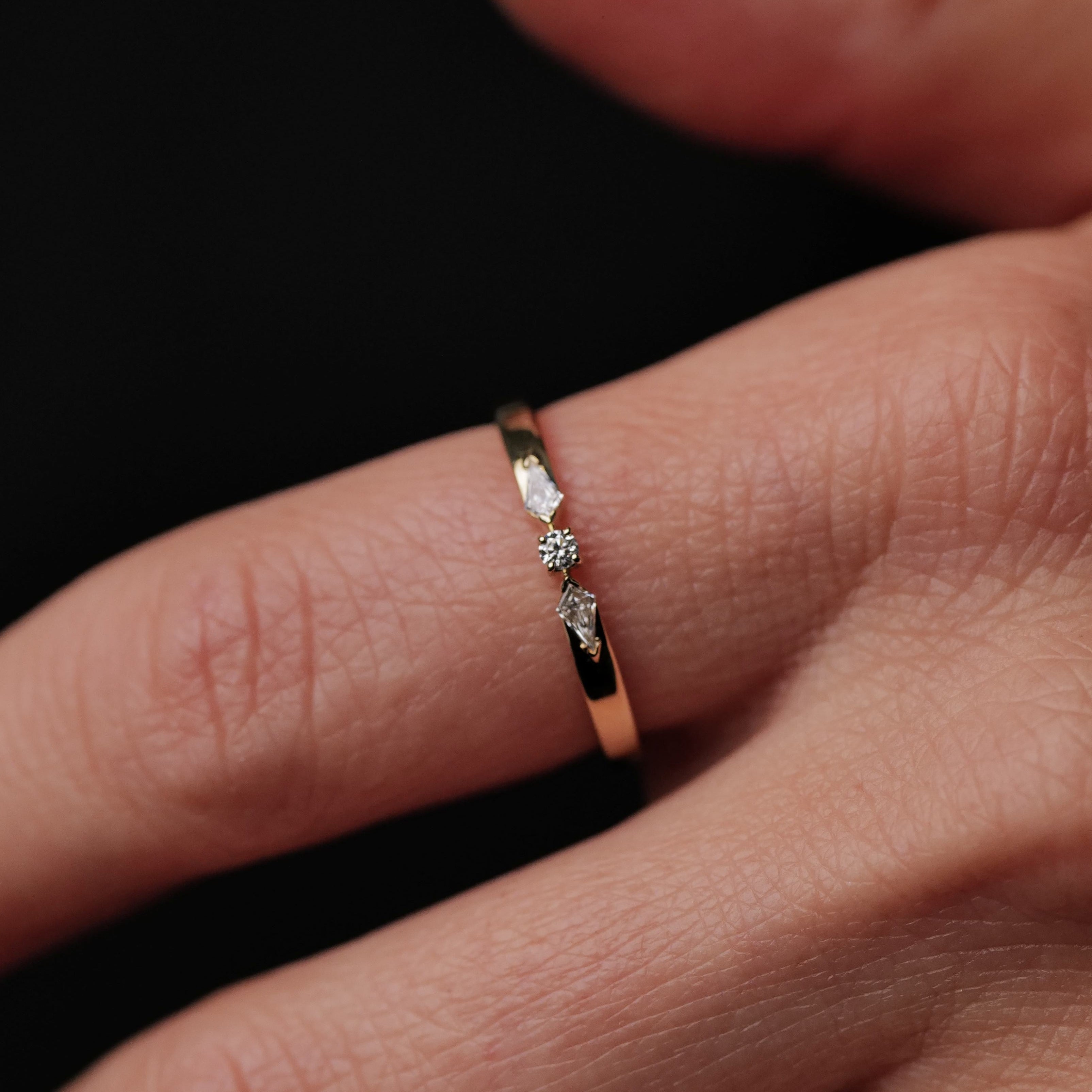The Fiat Lux Petite Nova Ring is a 14K gold ring set with three small diamonds on a black background.
