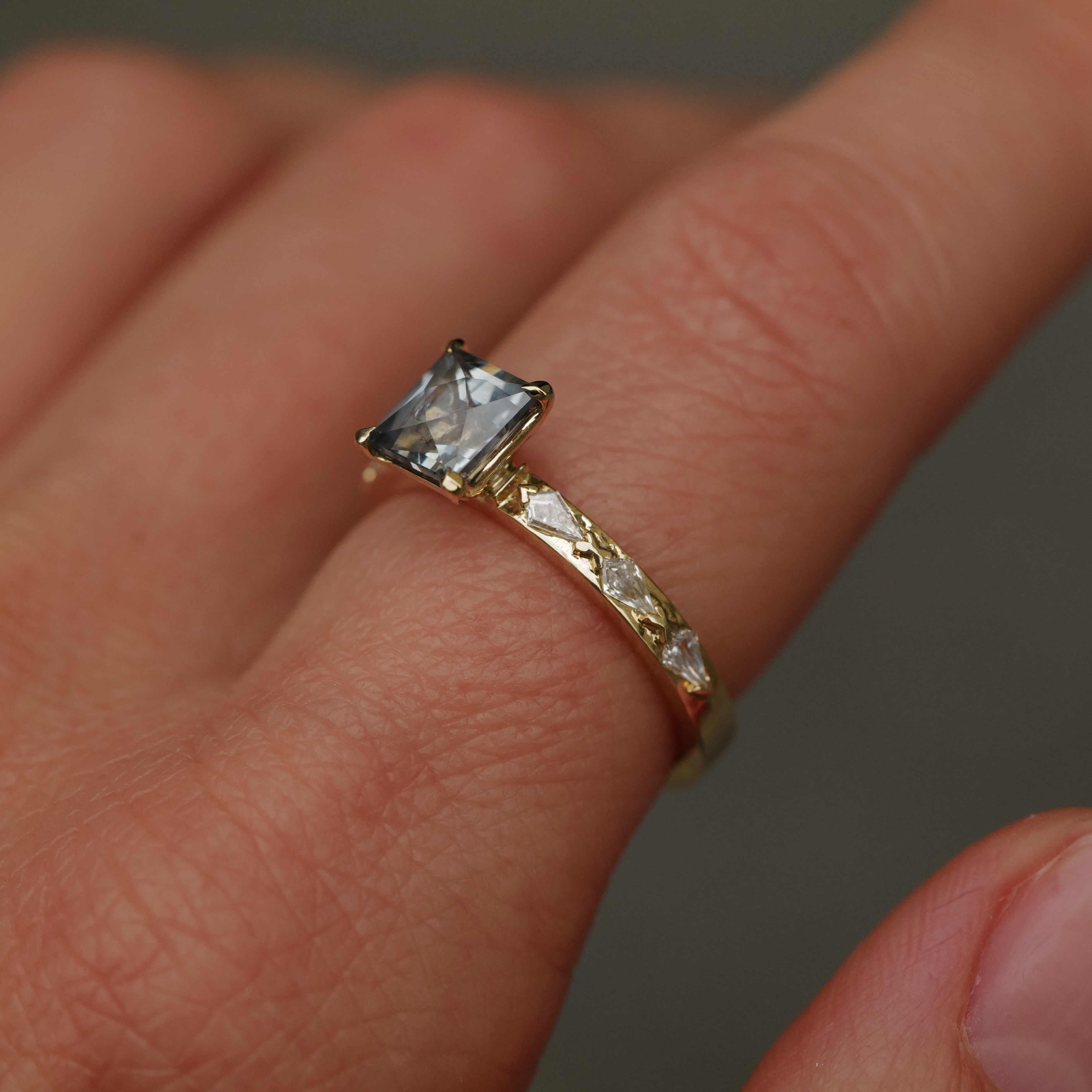 The Fiat Lux Classic Theia Ring - Aqua Sapphire (1.41ct) glows with blue and clear stones on a persons finger.