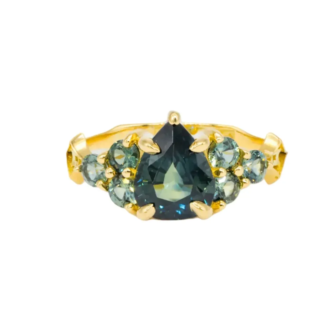 The Digby & Iona Nico Ring showcases a 2.07ct teal pear sapphire with smaller green stones set in 18K gold.