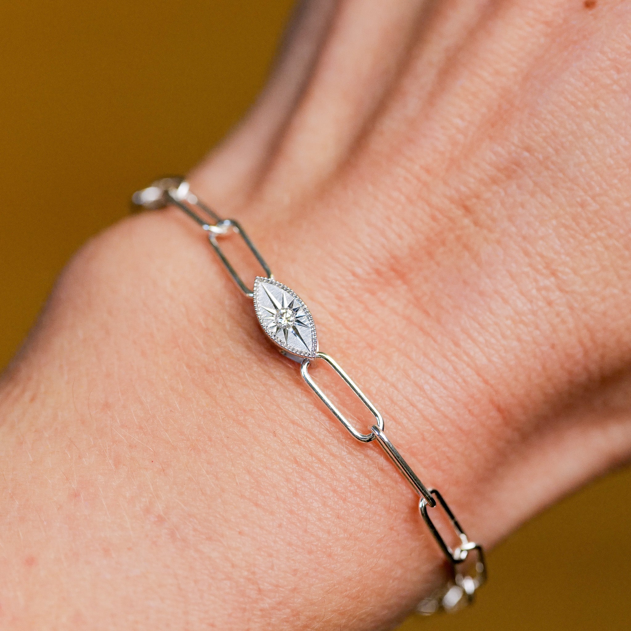 The Grande Mati Bracelet (G) by Fiat Lux is a silver chain with an oval starburst charm, ideal for minimalist styling.