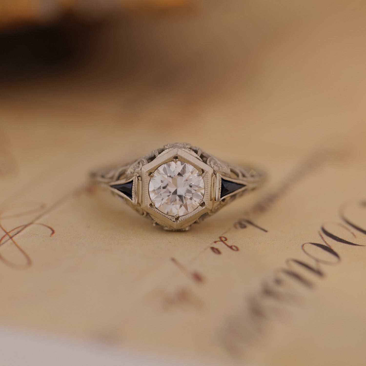 The Vintage Art Deco Botanical Hexagon Ring with Old European Cut diamond sits atop handwritten paper.