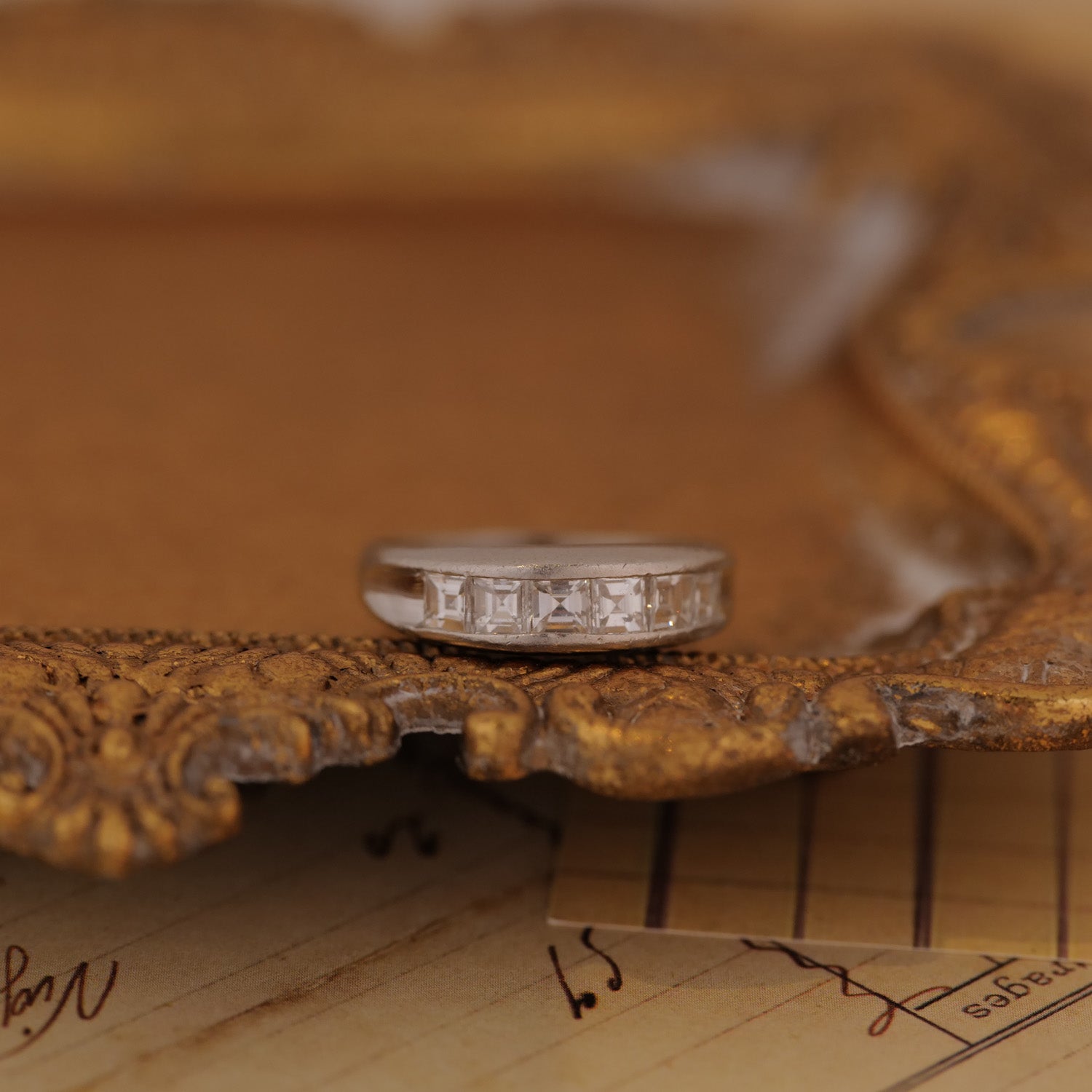 The Vintage Channel Set Carré Diamond Ring features a silver setting with carré diamonds on an ornate gold frame.