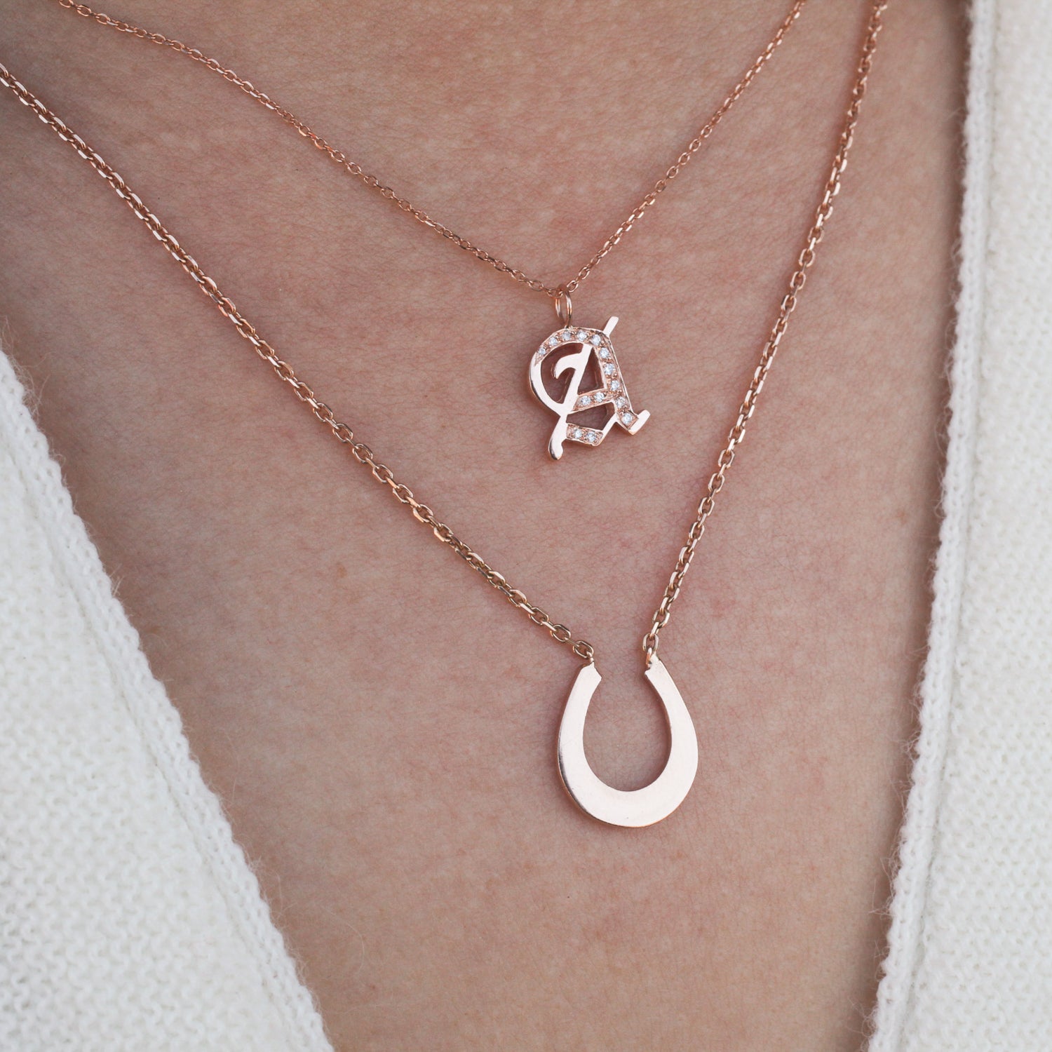 Georgie Golds Ideogram Charm: stacked 14K gold necklaces—horseshoe pendant & crystal A charm.