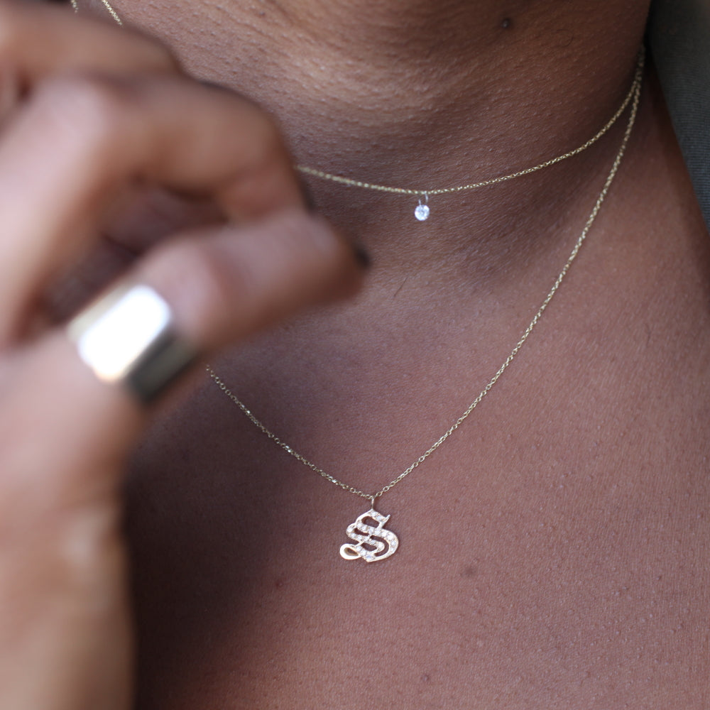 Close-up of Georgie Gold 14K necklaces—one with the Ideogram Charm, one with an “SS” pendant—layered for style.