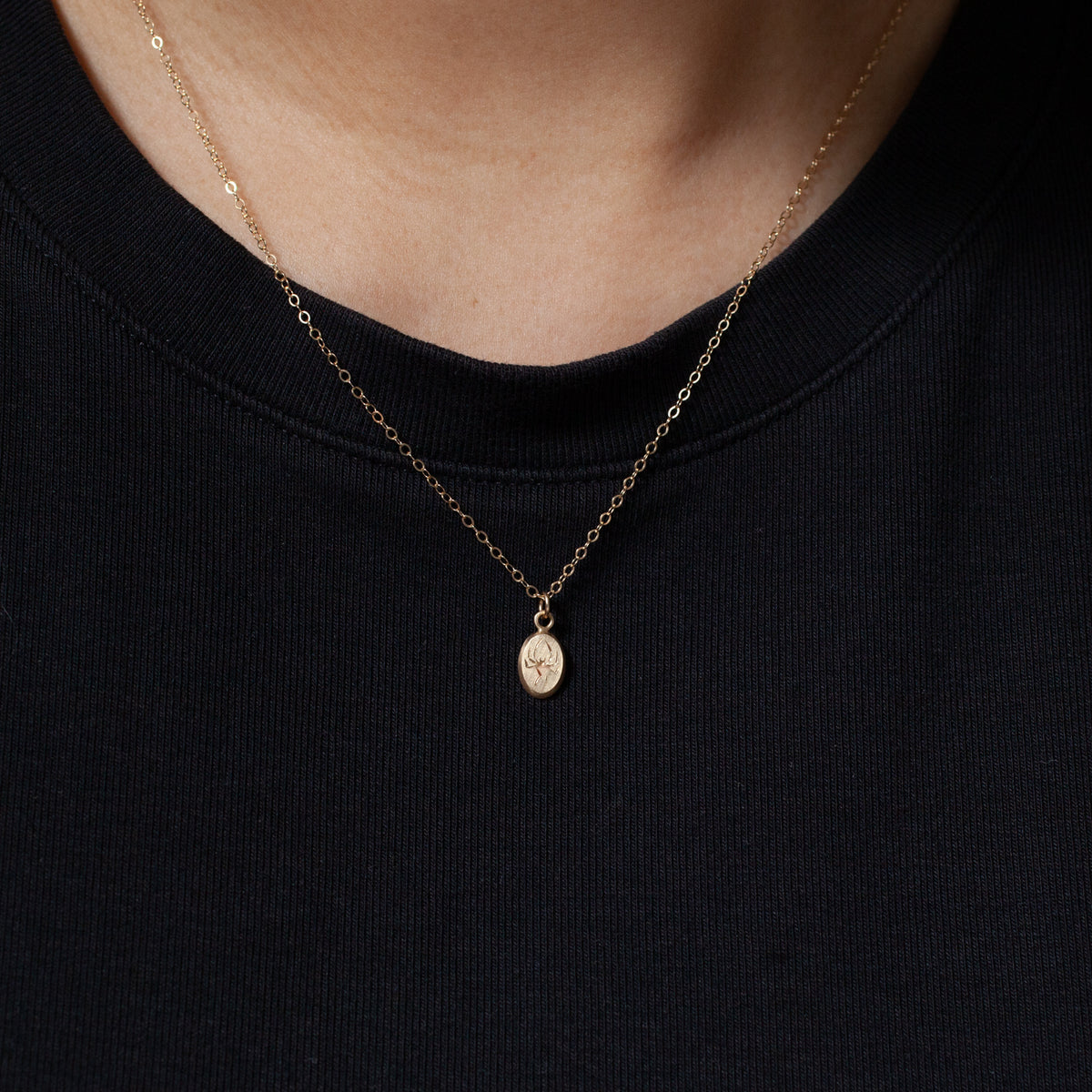 Blue Blue Driver’s Tiniest Spider Necklace adds subtle charm over a black crew-neck for effortless elegance.