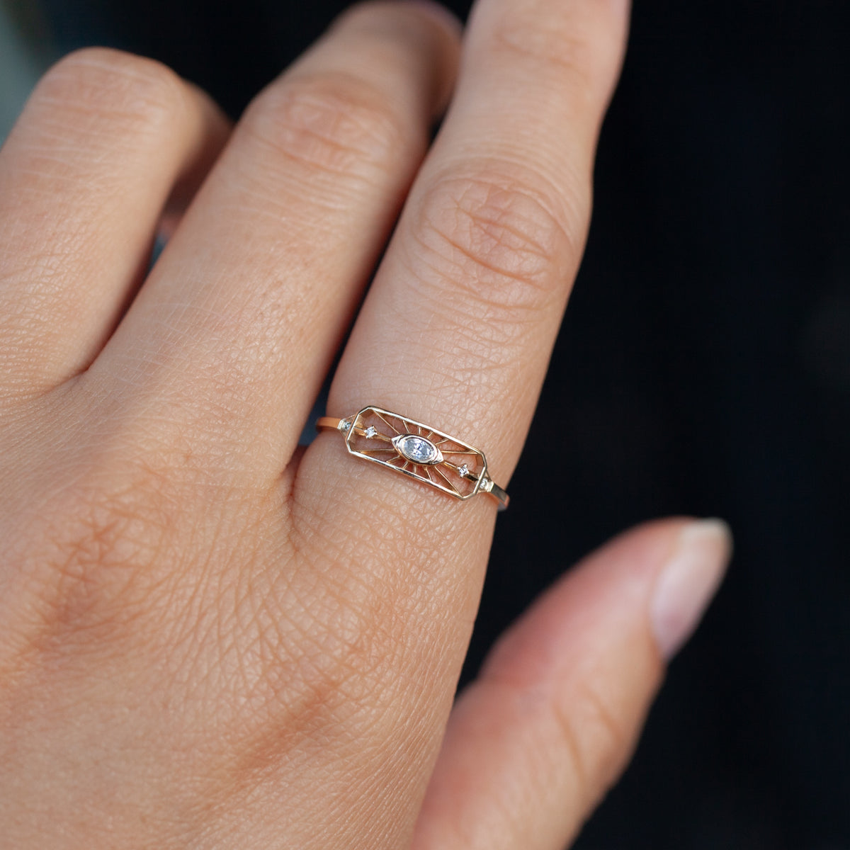 A Celine Daoust Dream Maker Open Eye Ring in 14k yellow gold with an eye-shaped center, small diamond, and ray details.