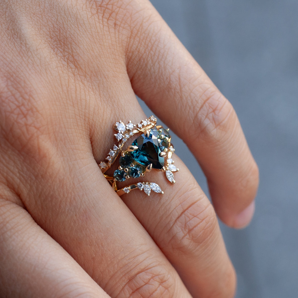 Nico Ring - Teal Pear Sapphire (2.07ct) worn on a finger, featuring a pear-shaped teal sapphire in 18K gold with diamonds.