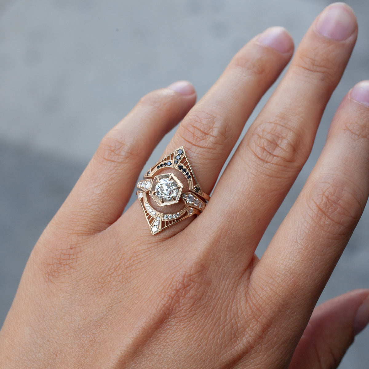 Hand wears DMD Metal Hex Bezel Ring with 1.22ct Old European Cut diamond, black accents; blurred background.