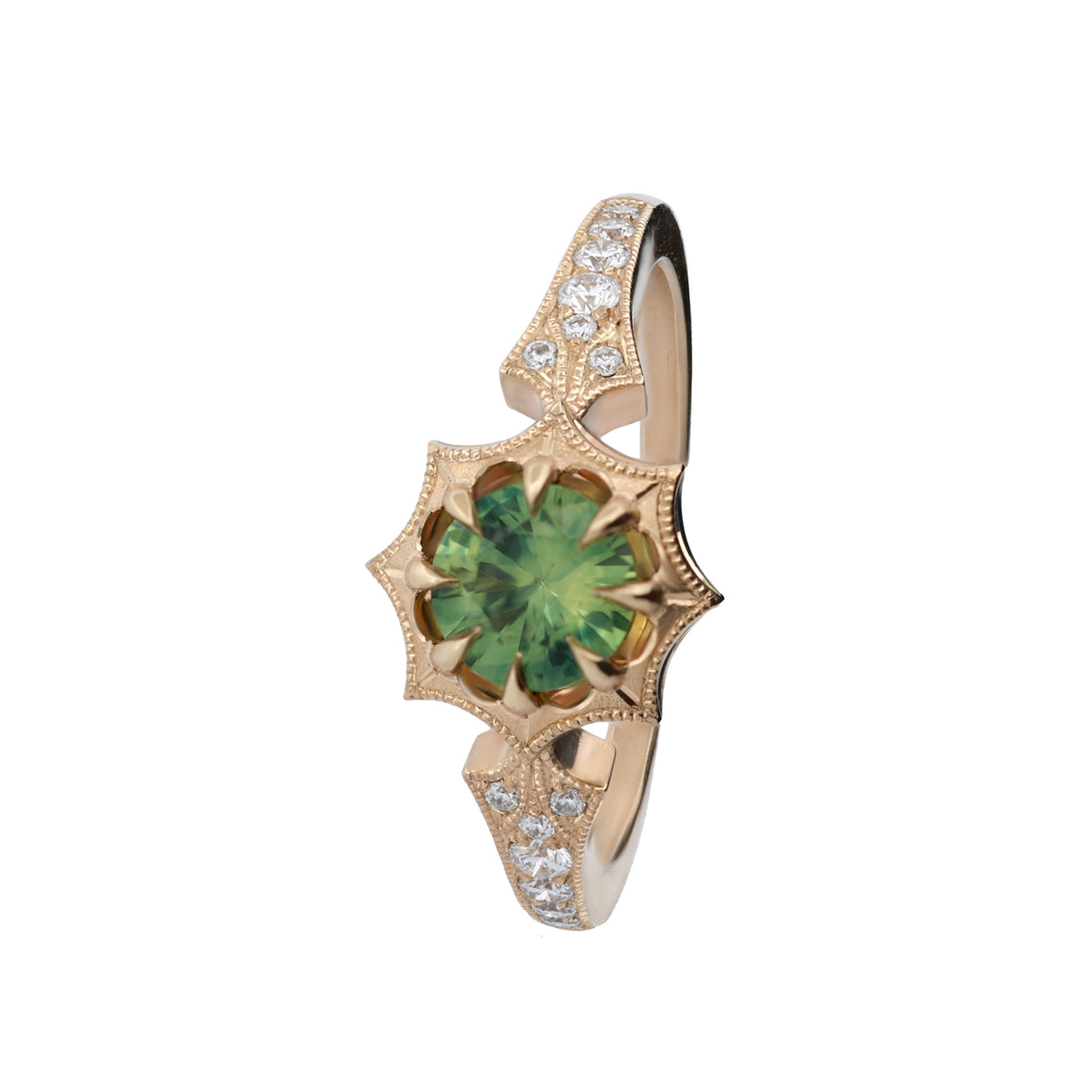 A gold ring featuring a central green gemstone in a floral, starburst-like setting, accented with small clear stones along the band, shown on a plain white background.