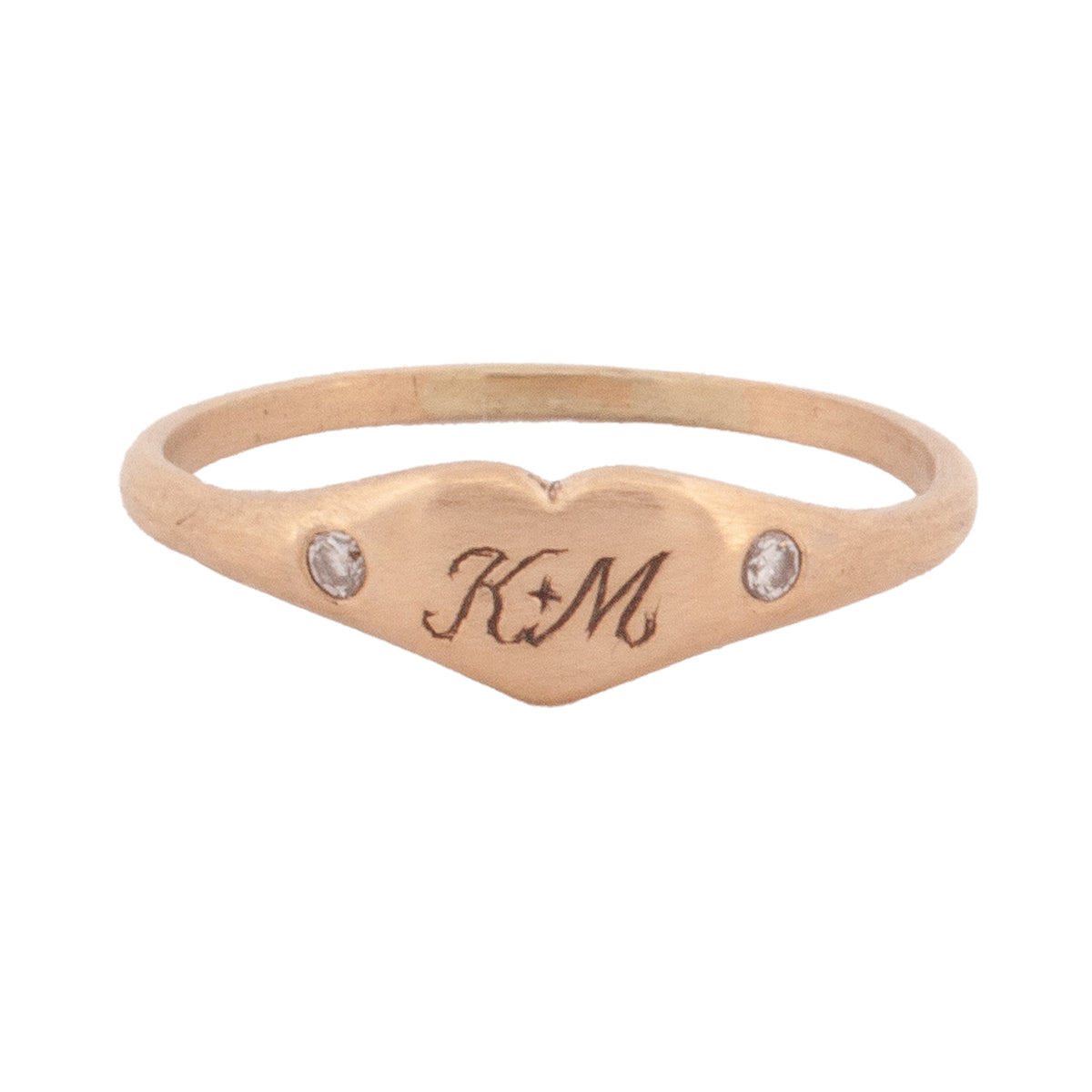 Daisy San Luis Littlest Heart Pinky Ring in 14k gold, heart-shaped with K+M engraving and a small stone on each side.