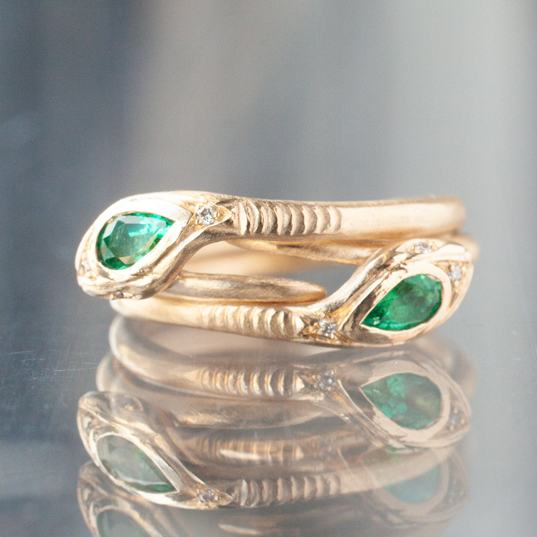 Victorias Fede Ring - Emerald Pear by Daisy San Luis shimmers with emerald eyes, beautifully reflected on glass.
