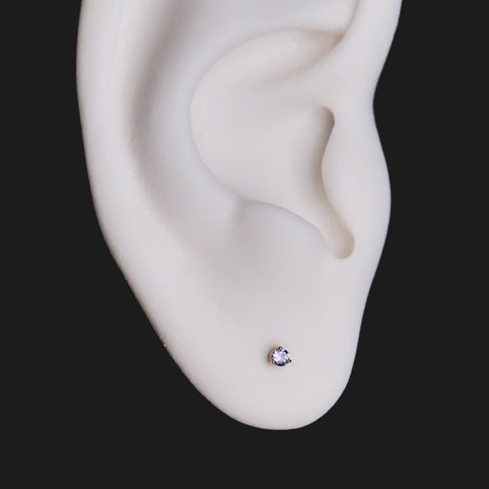 Fiat Lux 3 Prong Round Colored Gems (2mm) earring on white artificial ear, shown against a black background.