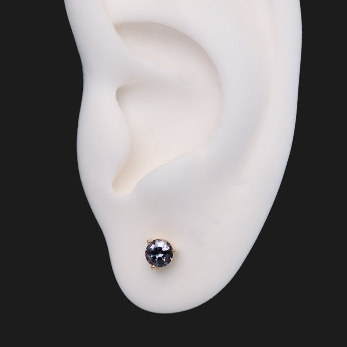 Fiat Lux 3 Prong Round - Alexandrite labret stud in a purple-grey, 14K gold setting on a white ear model.
