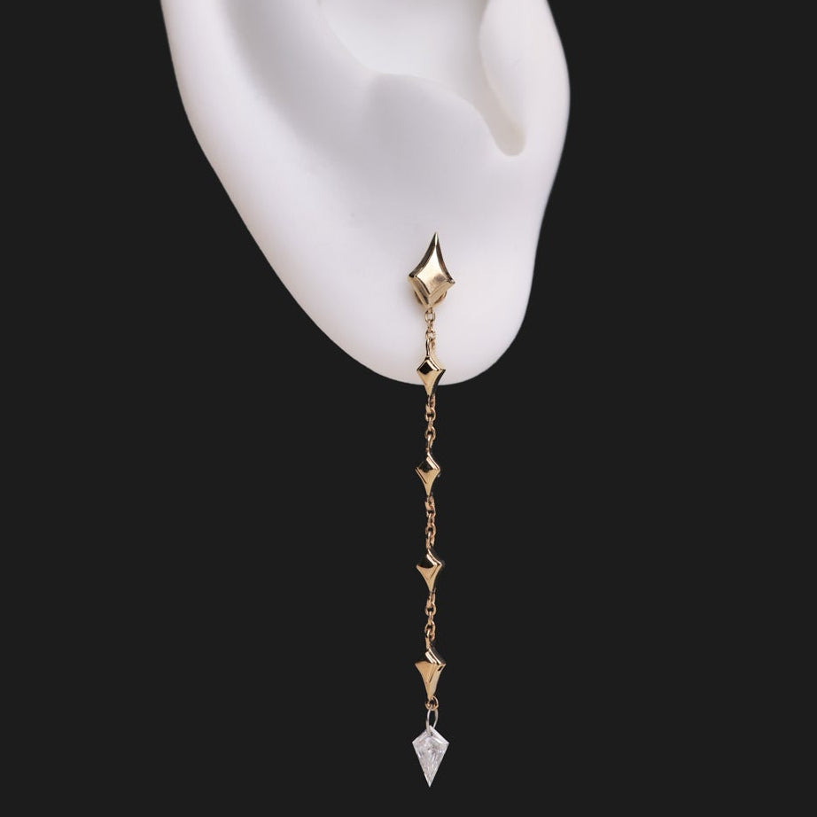 A Fiat Lux Constellation Kite Dangle: 14K gold chain earring with geometric links and a single diamond kite drop on an ear.