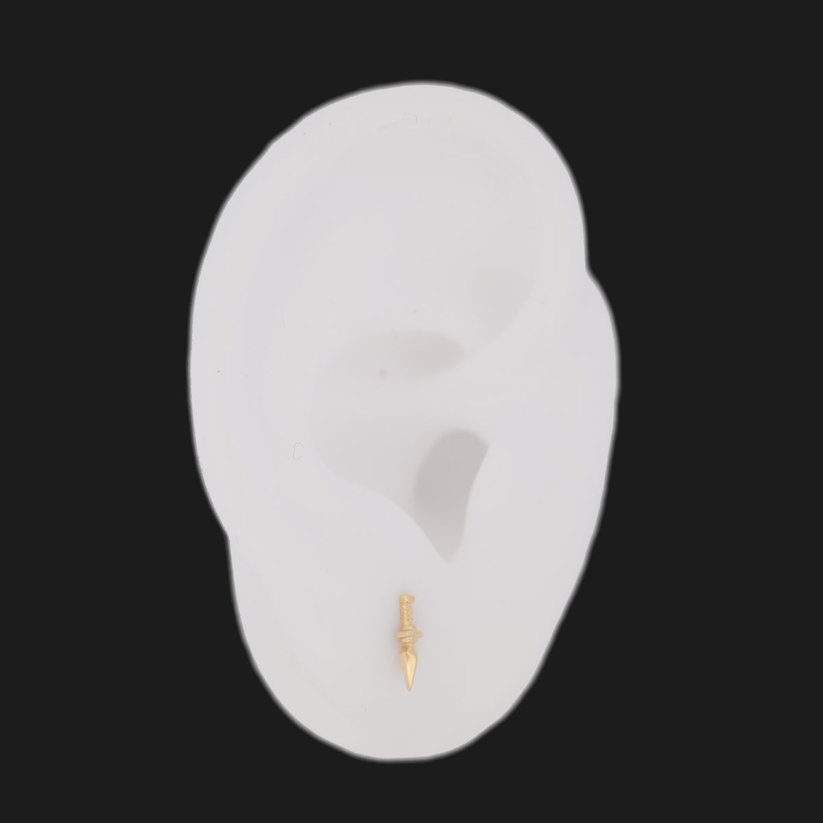 14K gold Dagger Stud dagger-shaped flatback earring worn in a model earlobe.