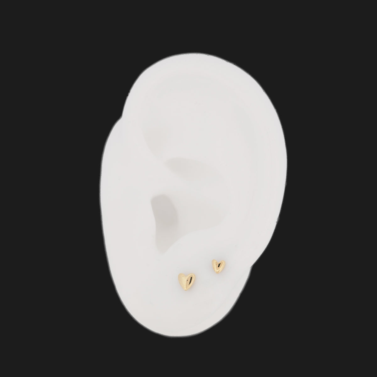 Fiat Lux Classic Puffy Heart (4mm) 14K gold stud earrings on a white ear model.