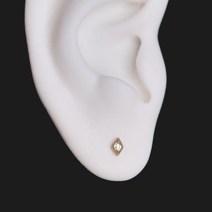 Serpentra Scale Stud - Marquise 14K gold earring with a central stone in a decorative border, worn in an earlobe.