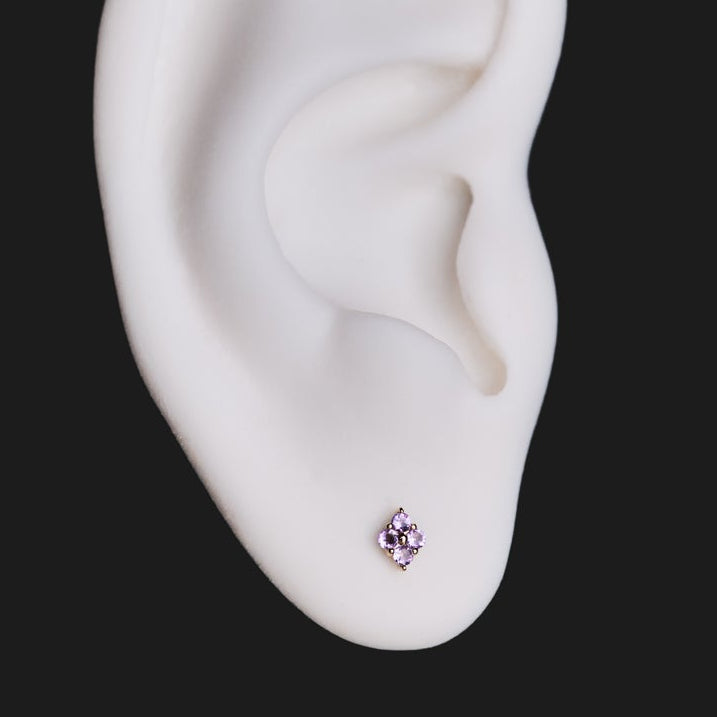 A white model ear wears Fiat Lux’s Grande Sirius Stud - Colored (1.5mm) in gold, shown on a black background.