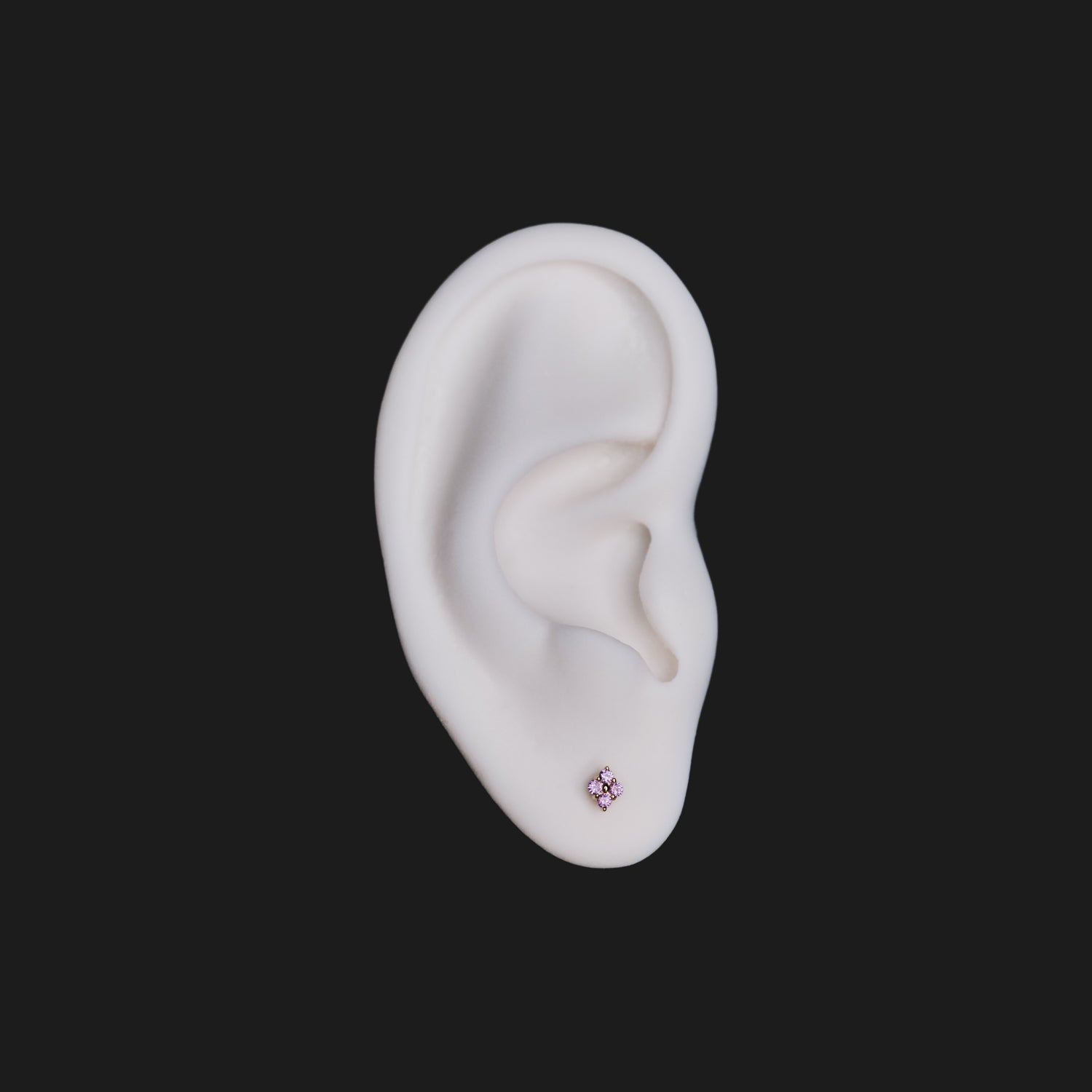 A white model ear with Fiat Lux Grande Sirius Stud (1.5mm, pink) flatback earring on a black background.