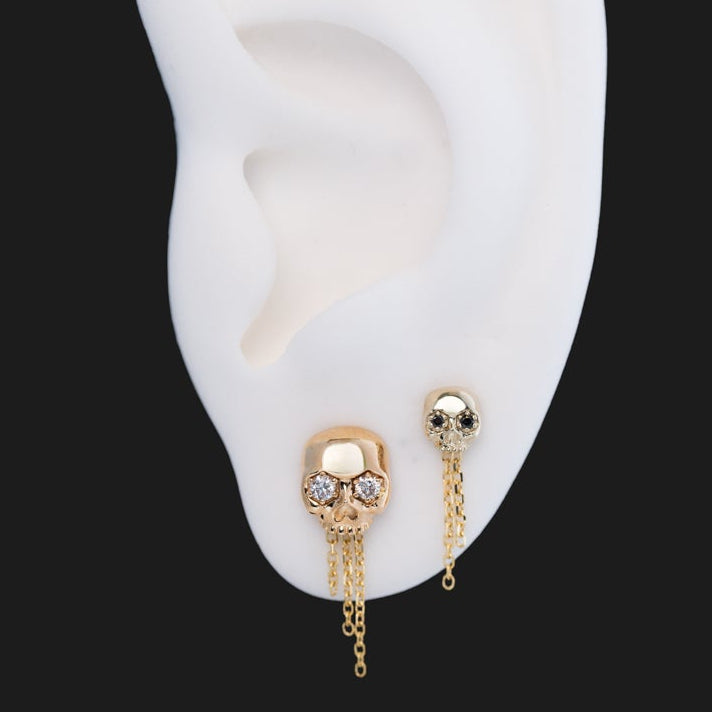 The Skull Stud - Petite by Fiat Lux: 14k gold skull earring with chains, flatback stud on white ear model.
