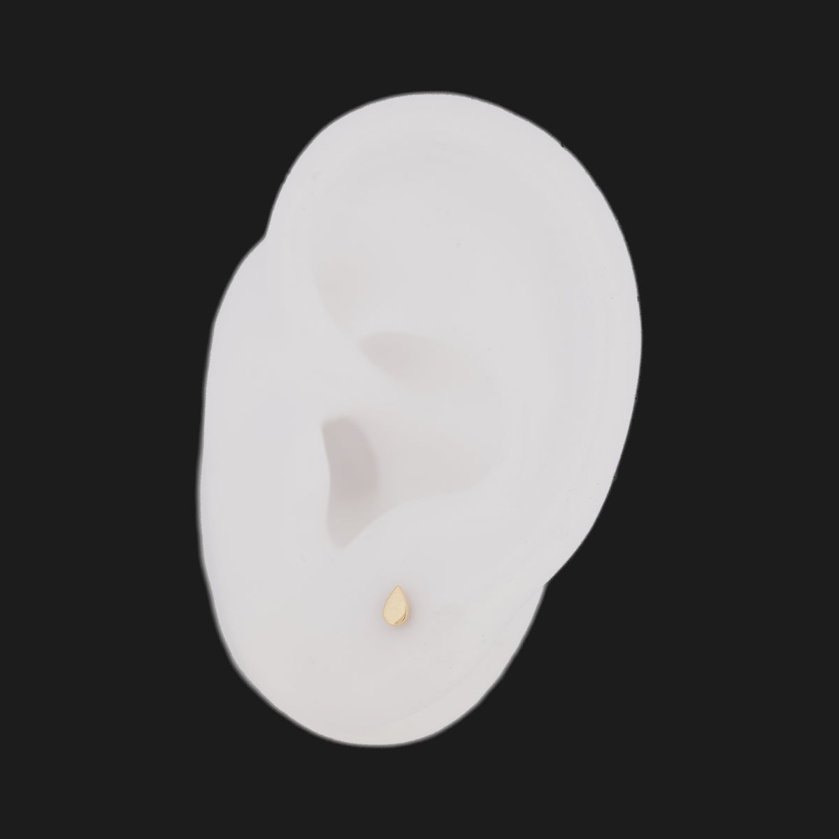 Classic Teardrop (4mm) 14K gold stud earring with a flatback, worn on a white ear model.