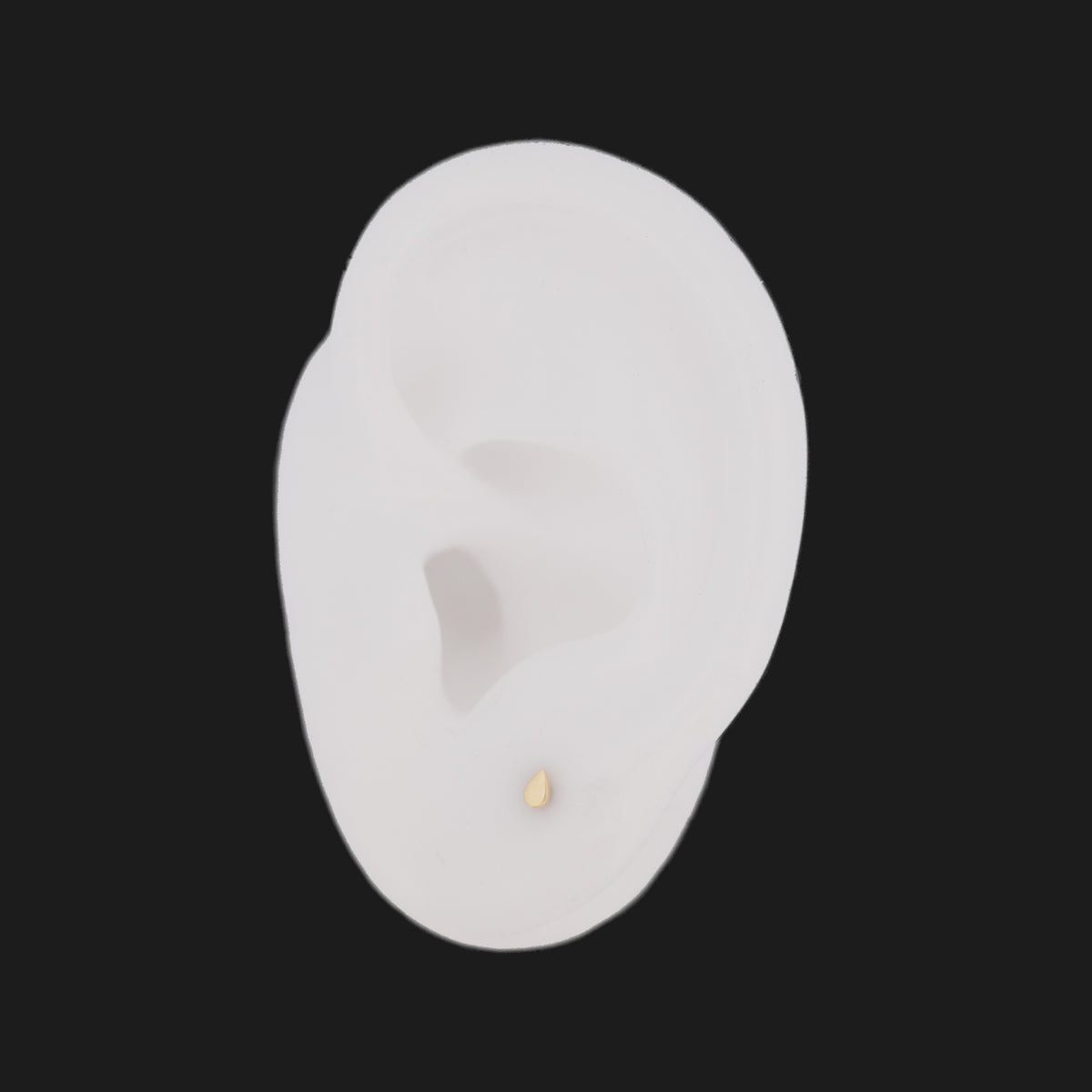 A small 14K gold Petite Teardrop (3mm) stud earring worn in a mannequin earlobe.
