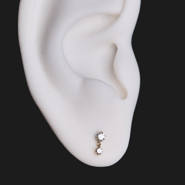 Fiat Lux Classic Twin Stars - White Diamond (2.5mm) studs on white model ear, set against a solid black background.