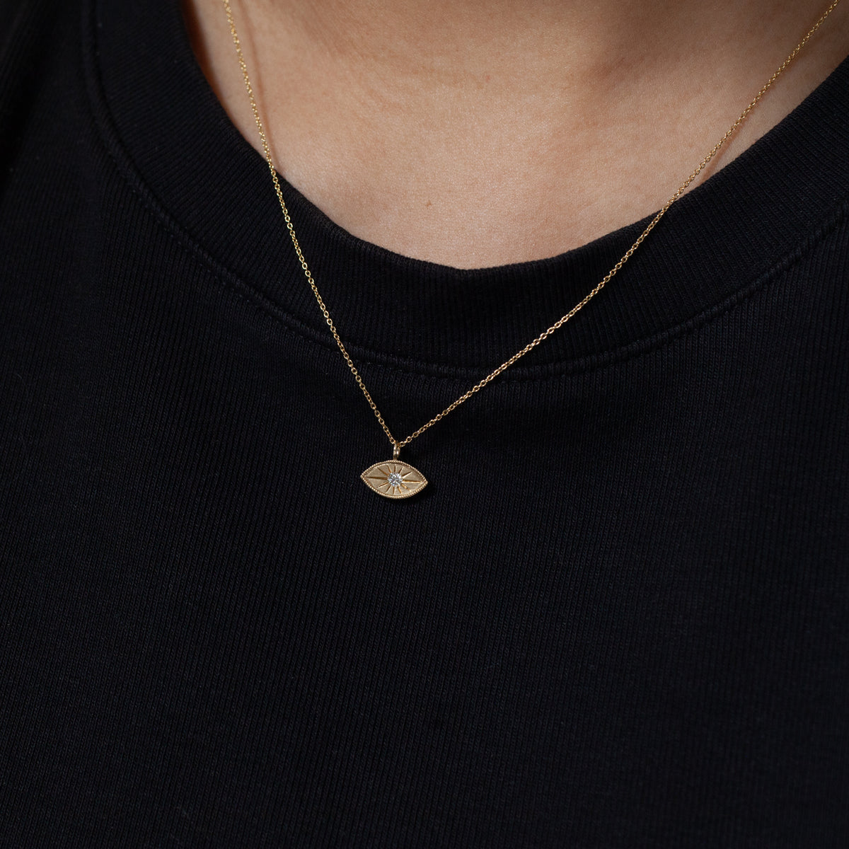 A minimalist look: Fiat Lux Mini Mati Necklace (G), an eye pendant, over a plain black shirt.