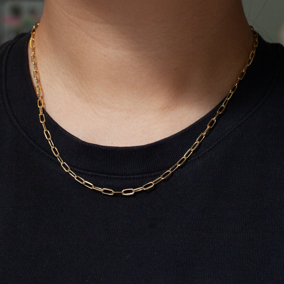 Close-up of a person wearing the Fiat Lux Grande Paperclip Chain and another gold necklace over a black crew neck.