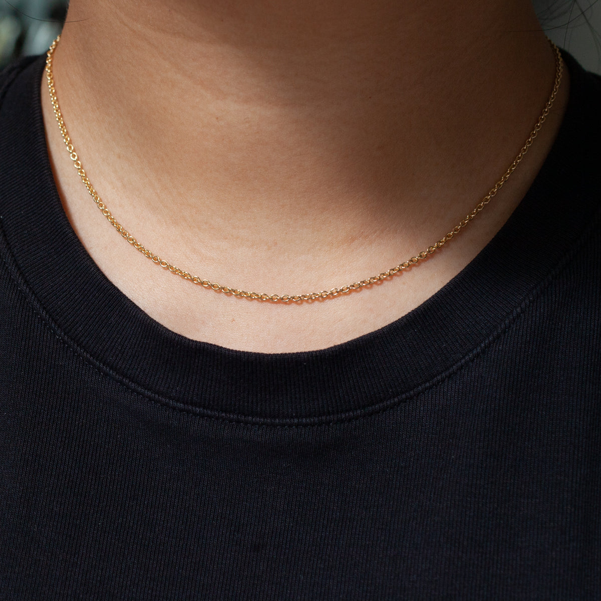 Someone wearing the Fiat Lux Grande Rolo Chain (14K) with a black crew-neck shirt.