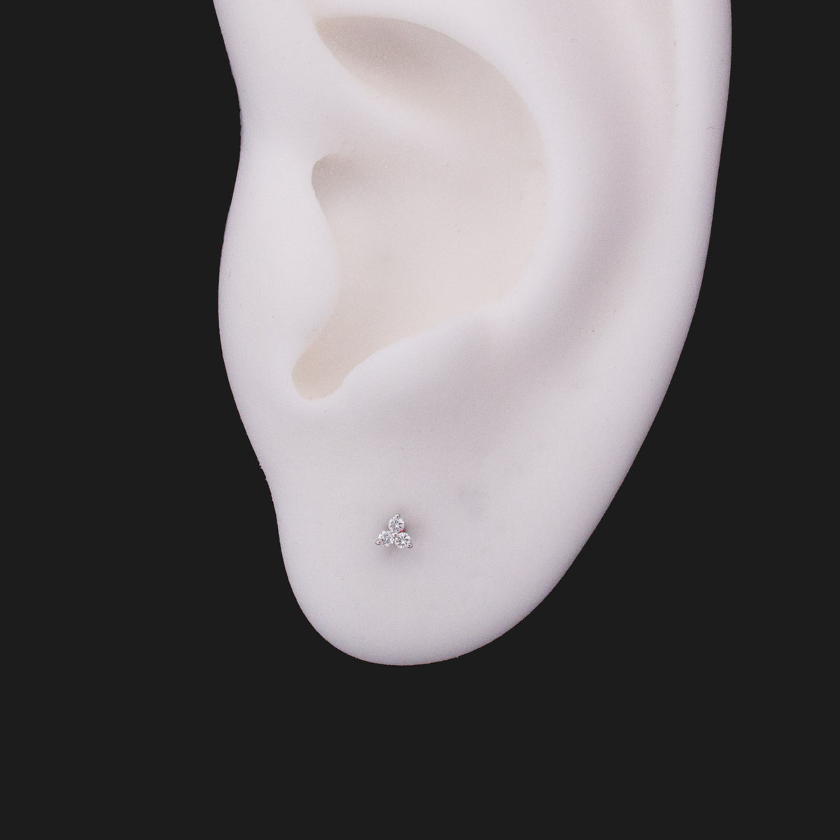 A Fiat Lux 3 Gem Cluster - White Diamond (1mm) stud earring in 14K gold on a white ear model.