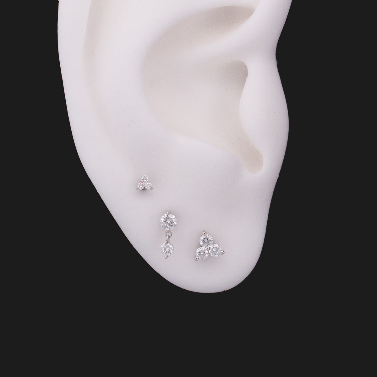 Three Classic Twin Stars - White Diamond (2.5mm) stud earrings arranged on an ear model.