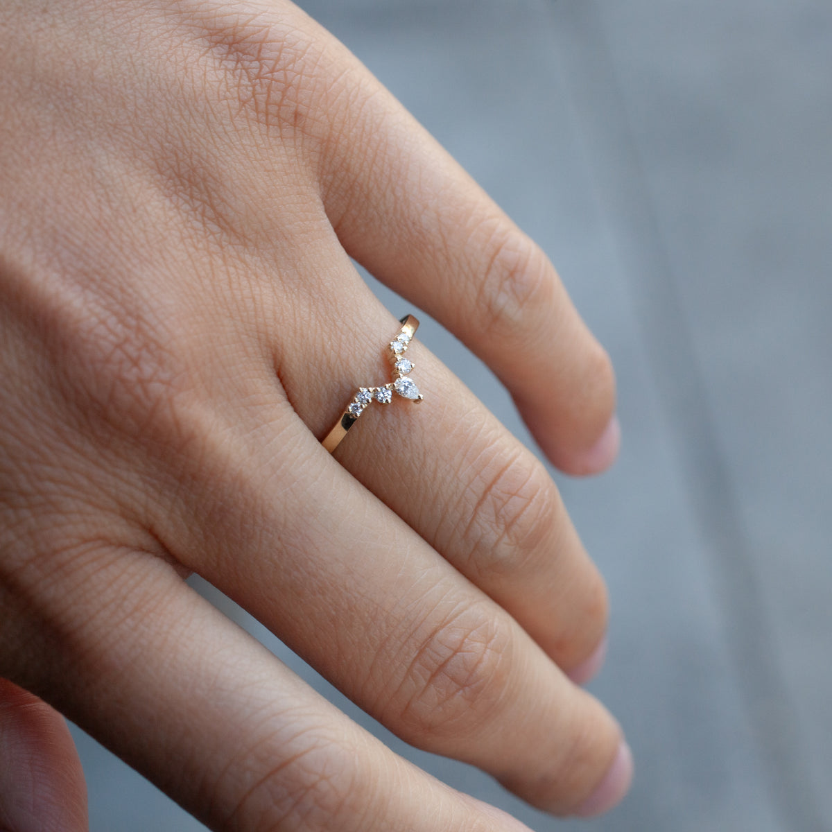 Fiat Lux Echo Tracer Ring: gold V-shaped band with small diamonds, shown on finger against a gray background.