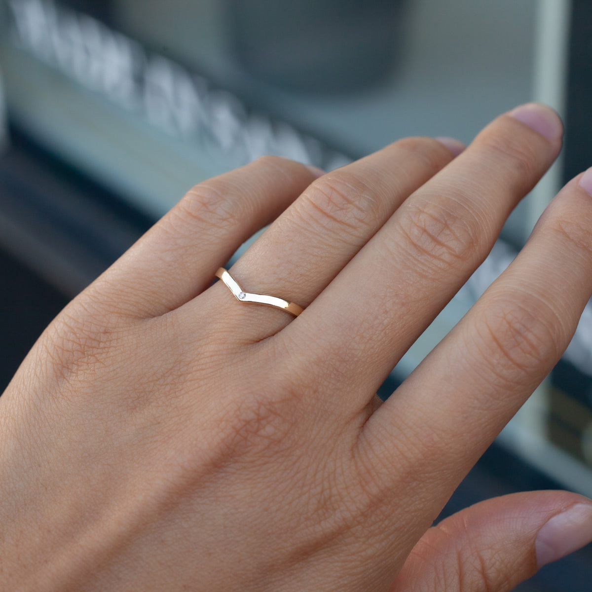 A hand wears the Fiat Lux Hazeline Ring - Diamond Point on the ring finger, against a softly blurred background.