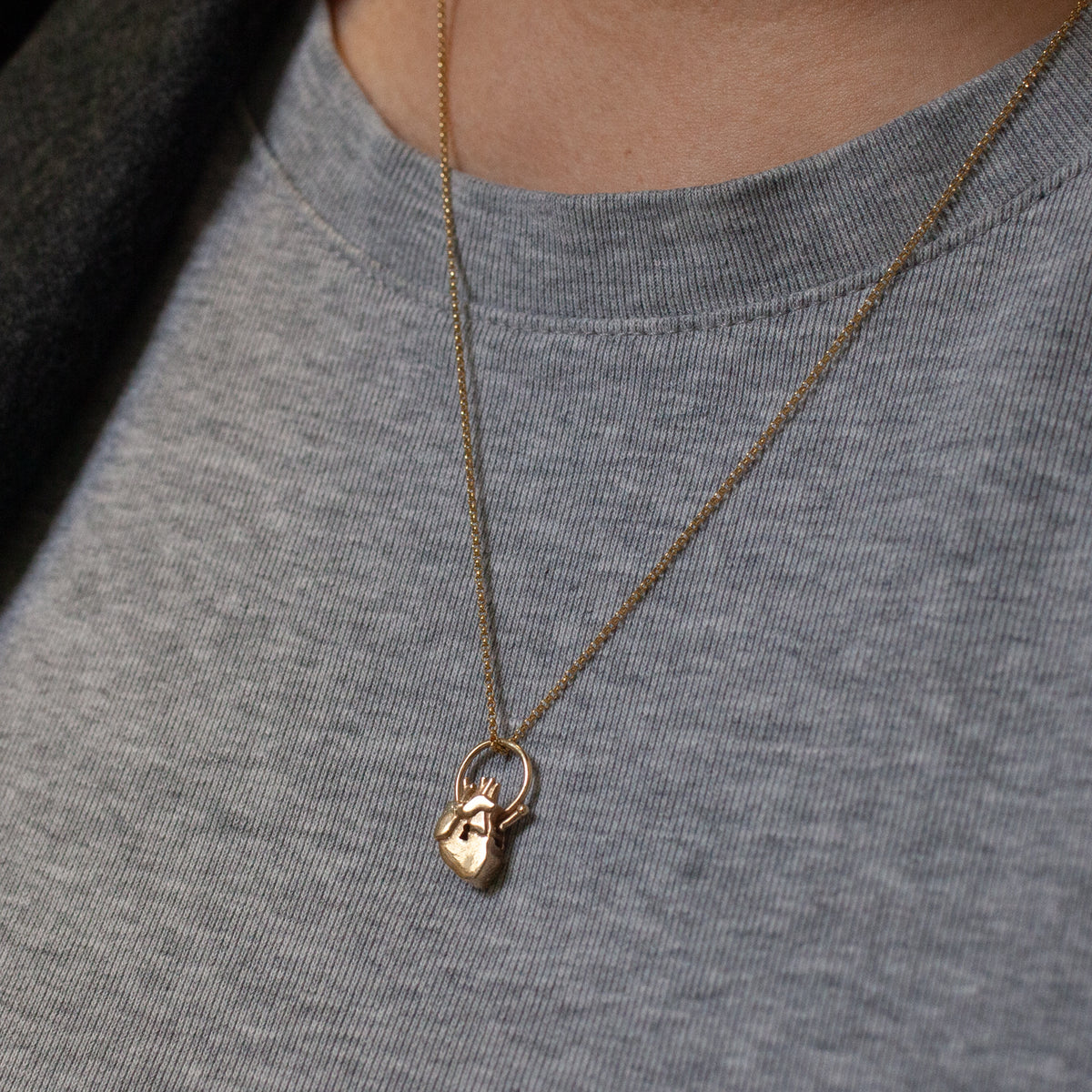 Anatomical Heart Lock Charm: a 14K gold necklace with an anatomically precise heart pendant featuring a small keyhole.