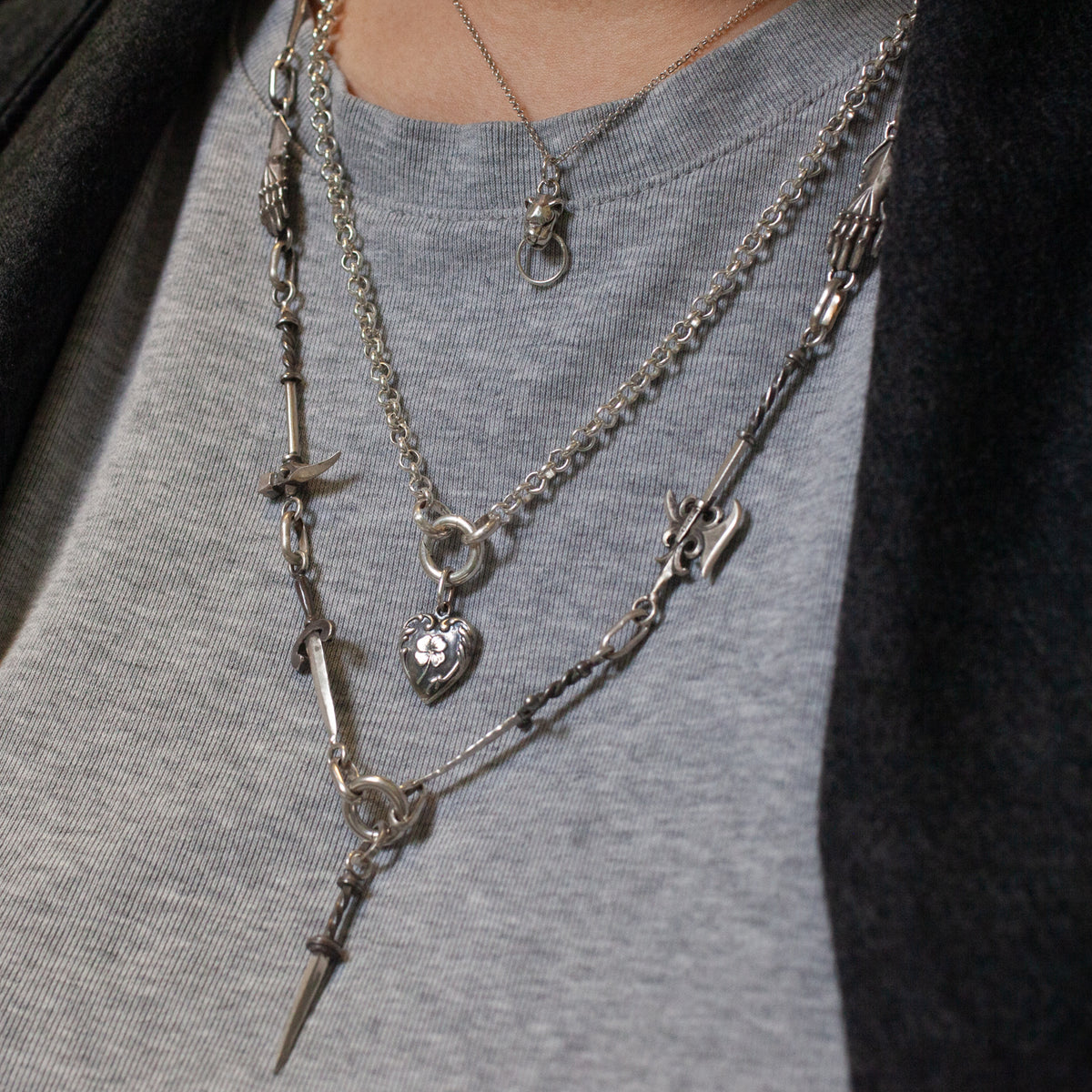 Sacred Order Potentia Door Knocker Necklace: three silver layered chains with lion, heart, and dagger charms.