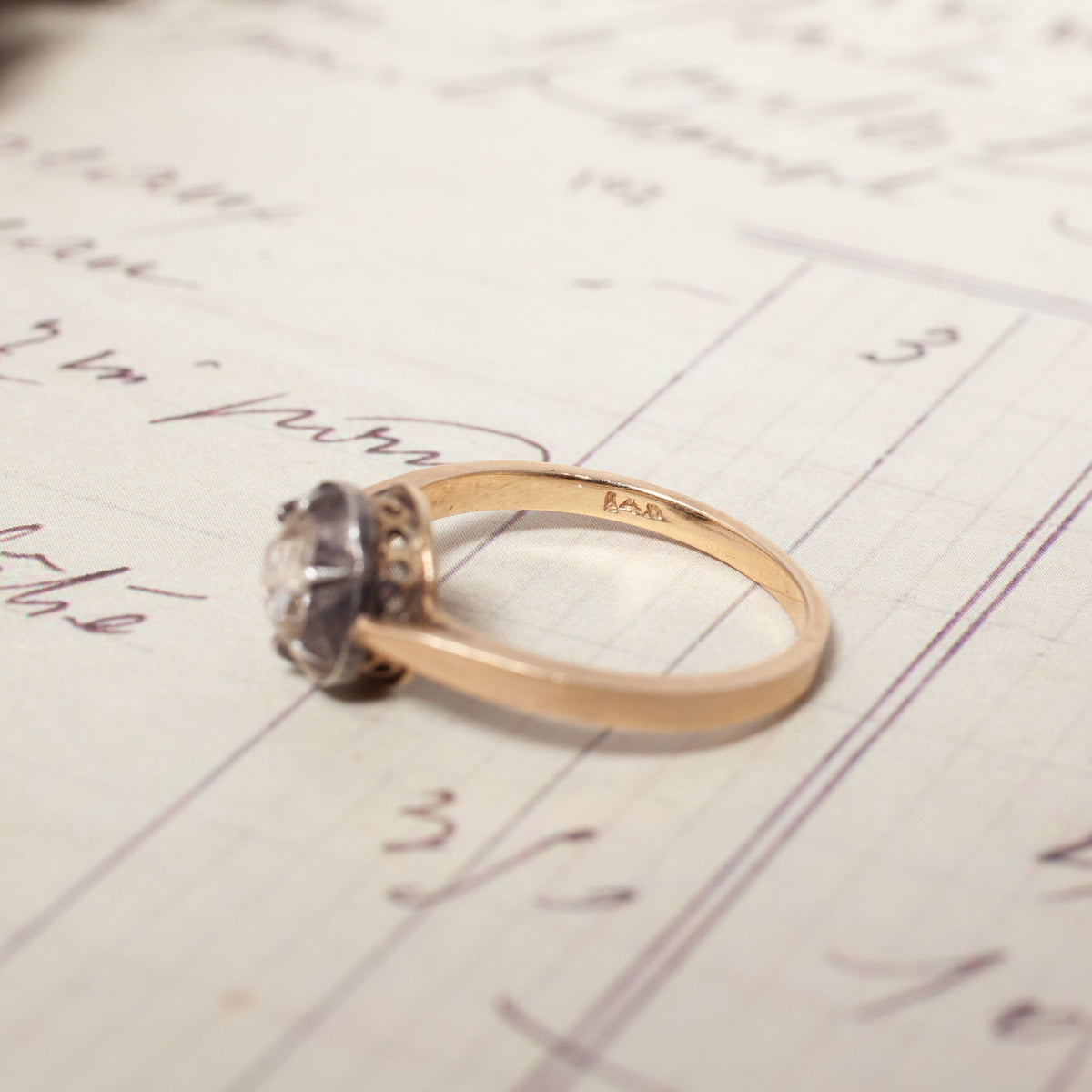 Antique Cut Down Collet Diamond Ring with a rose cut diamond in a bezel setting, resting on a sheet of handwritten paper.