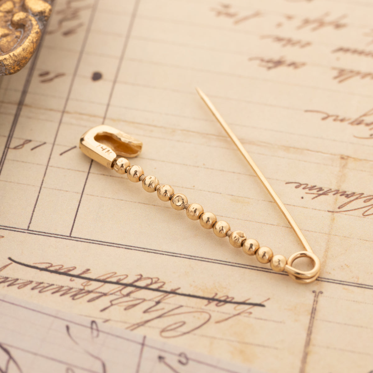 Vintage Beaded Safety Pin crafted from 14K gold with a row of small, spherical beads.
