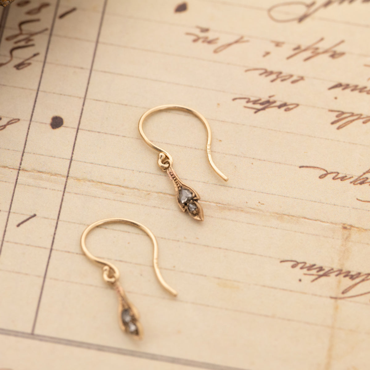 Antique Diamond Leaf Drop Earrings: two 14k gold drop earrings shaped like small leaves, each set with a dark gemstone.