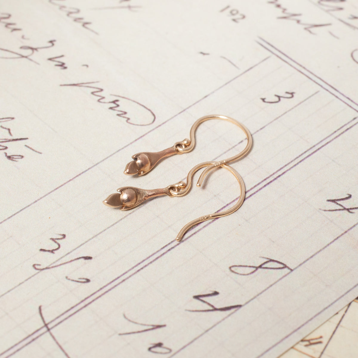 Antique Diamond Leaf Drop Earrings with bud-shaped charms resting on vintage lined stationery.